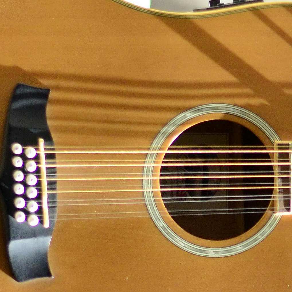 A closeup of the sound hole and bridge of a 12 string guitar