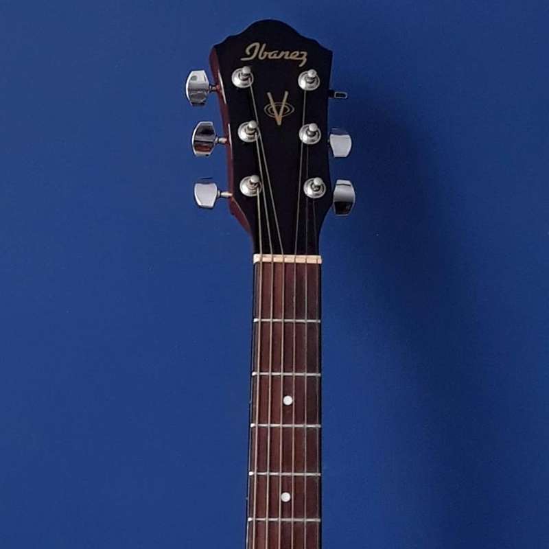 The headstock of an Ibanez acoustic guitar over a blue background