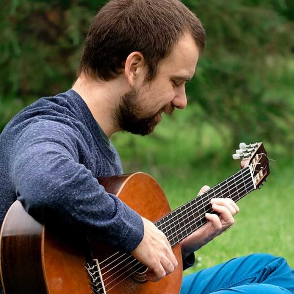 Expert guitarist Brett Vachon warming up by playing a fingerstyle guitar scale in the park