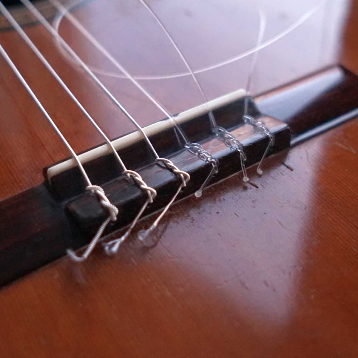 The bridge of the classical guitar showing tie-end nylon guitar strings