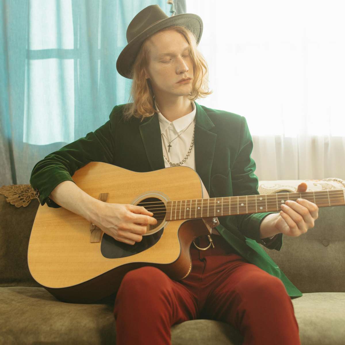 A man in a green suit practicing a basic fingerpicking pattern for beginners