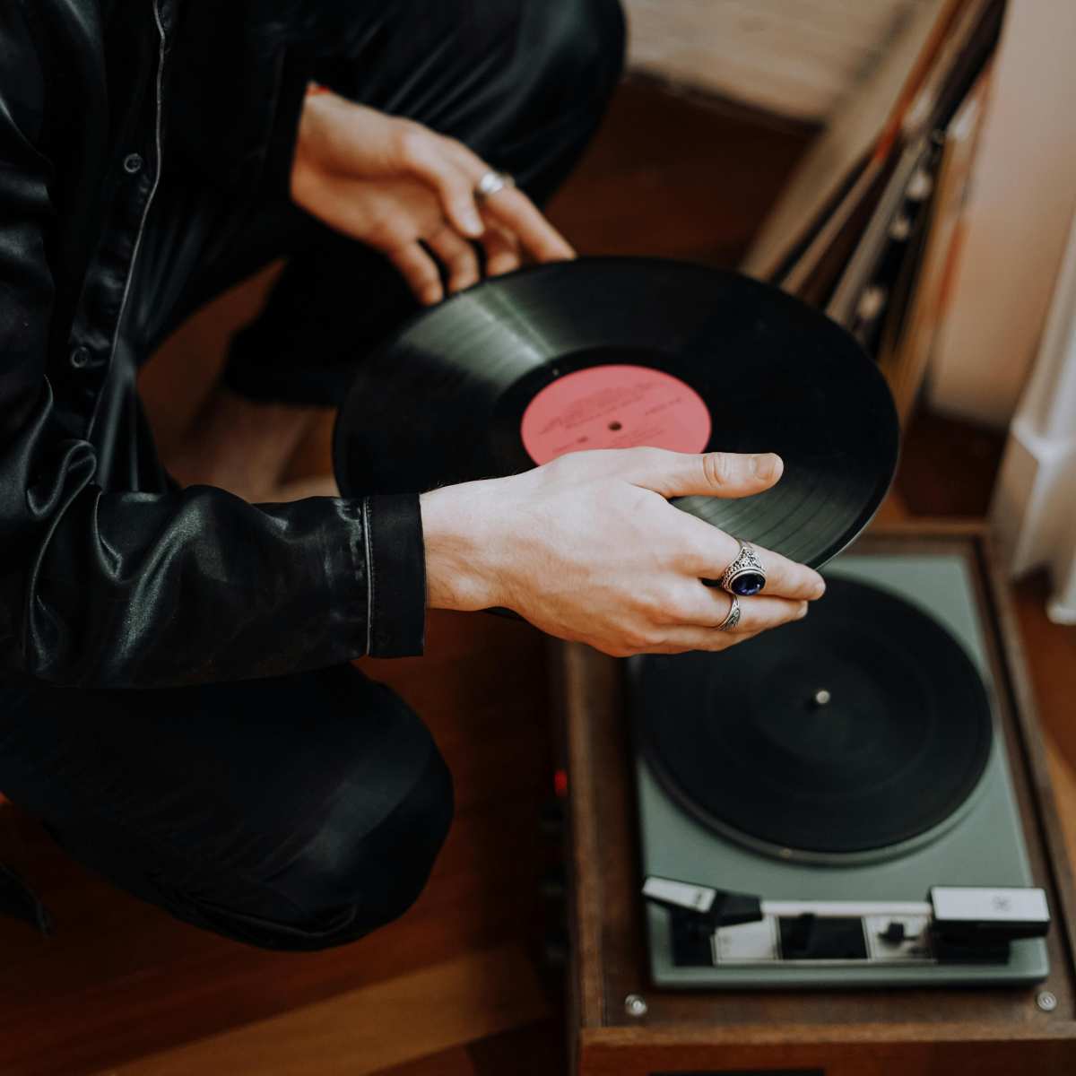 An image of a man holding a vinyl LP placing it inside a record player.